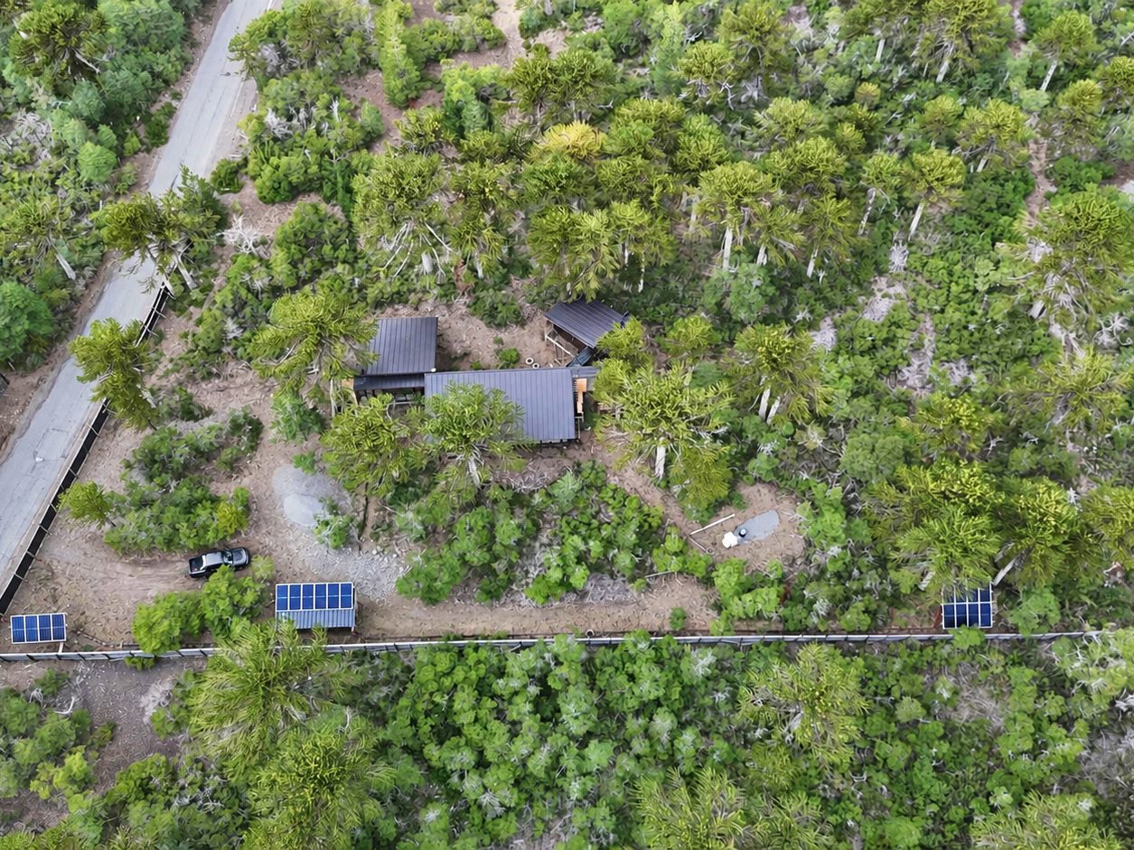 Vista aérea de la casa y los paneles en un terreno con bosque
