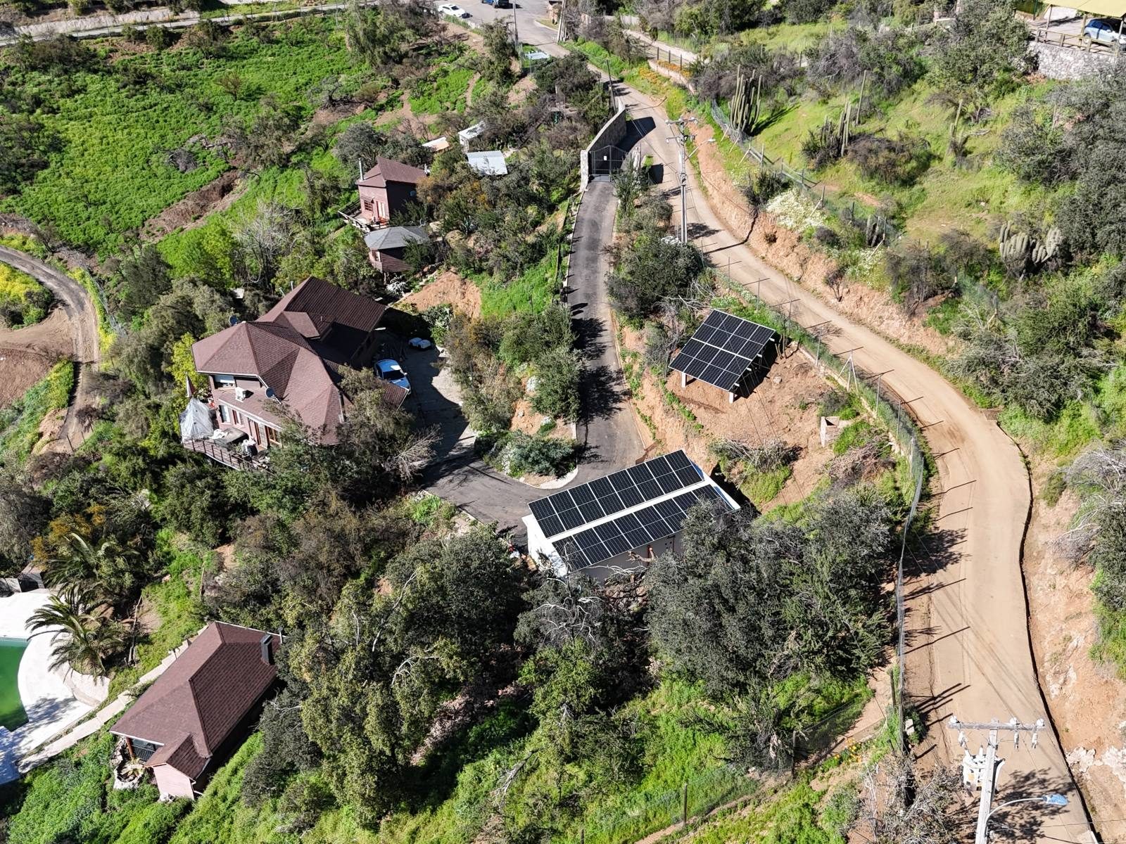 Vista aérea de una parcela con paneles sobre estructuras y sobre una bodega