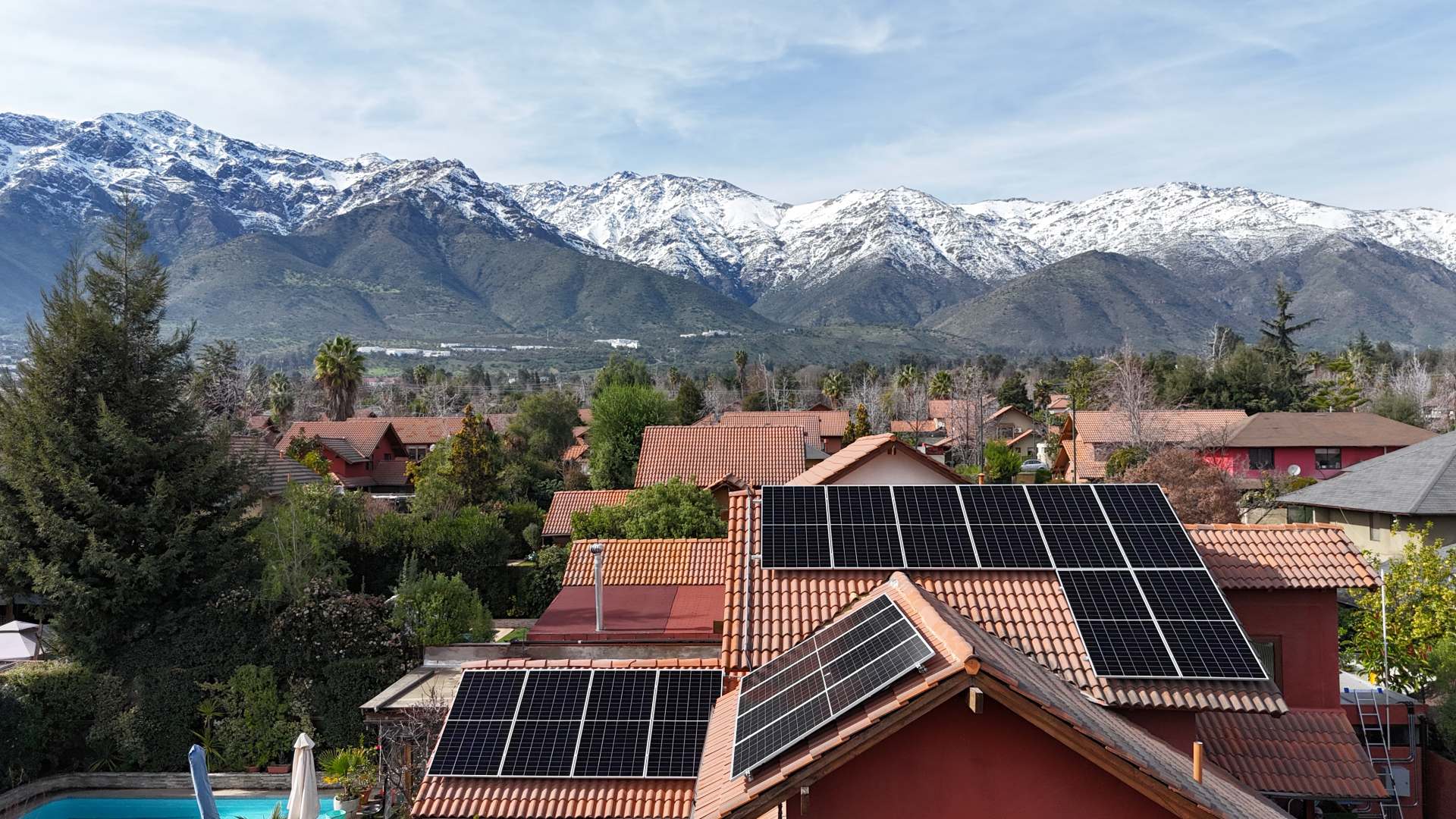 Paneles solares sobre el techo de una casa, con la cordillera nevada al fondo
